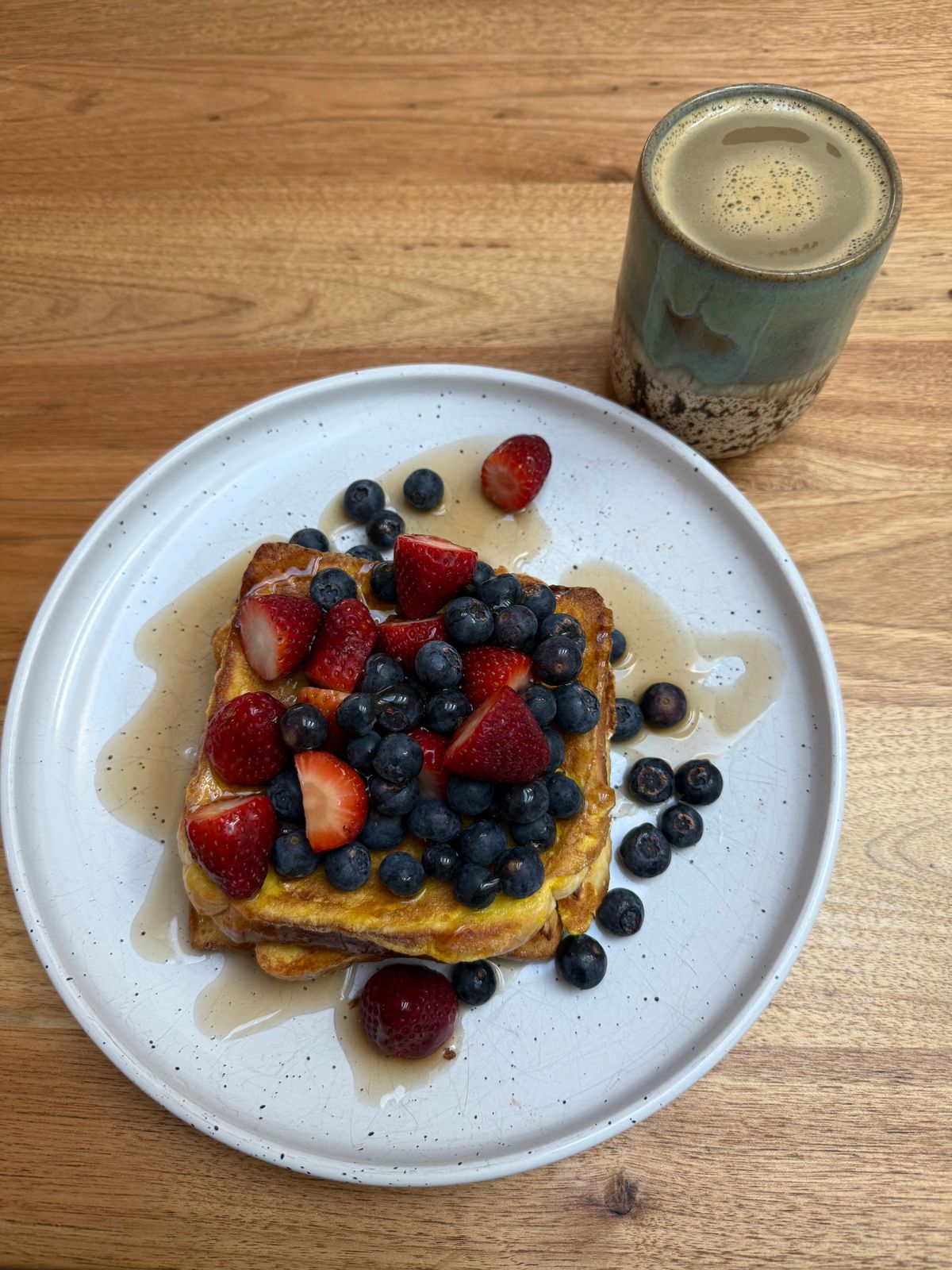 A prepared coffee beside berry-topped French toast