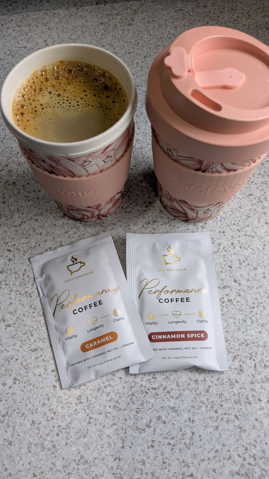 Two pink reusable cups beside Caramel and Cinnamon Spice Performance Coffee sachets