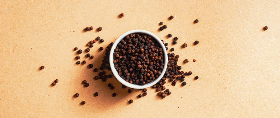 Black peppercorns in a white bowl