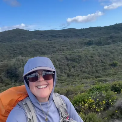 Customer-uploaded photo of a hiker wearing sunglasses in green hills