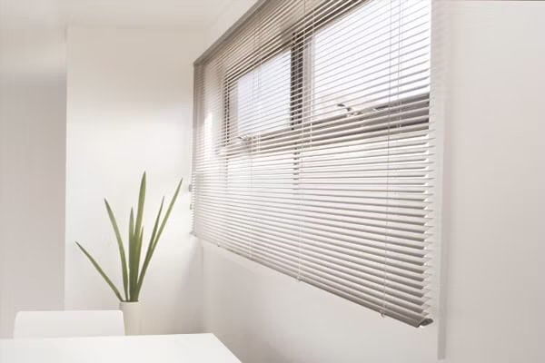Slimline Venetian blinds adjusting light at a window