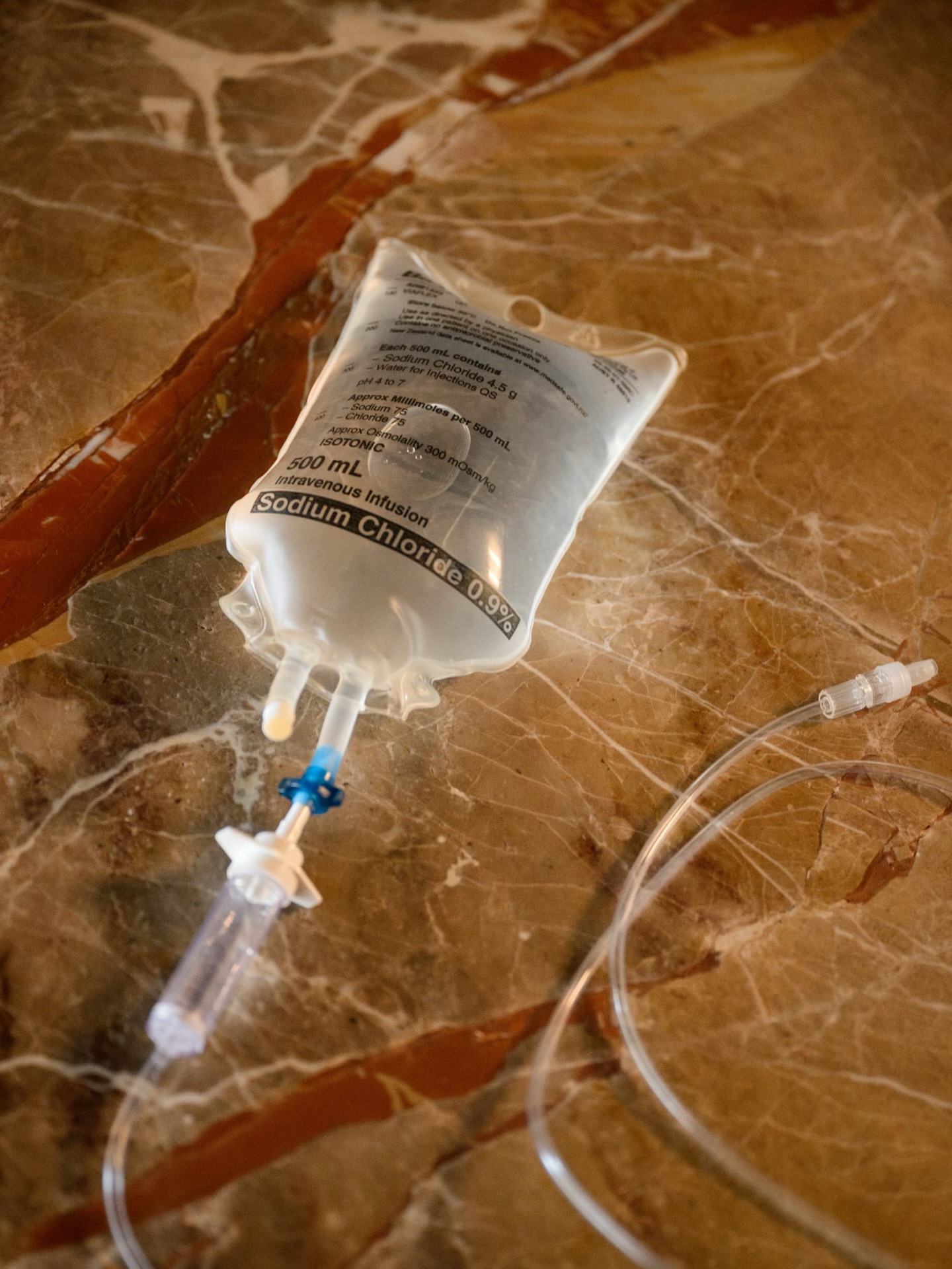 A saline infusion bag and tubing arranged on warm stone