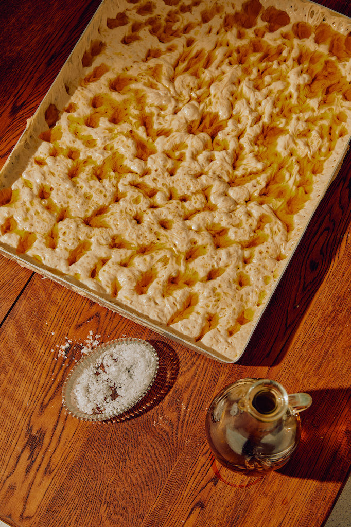 Freshly baked focaccia with a cruet of golden olive oil and flaky salt