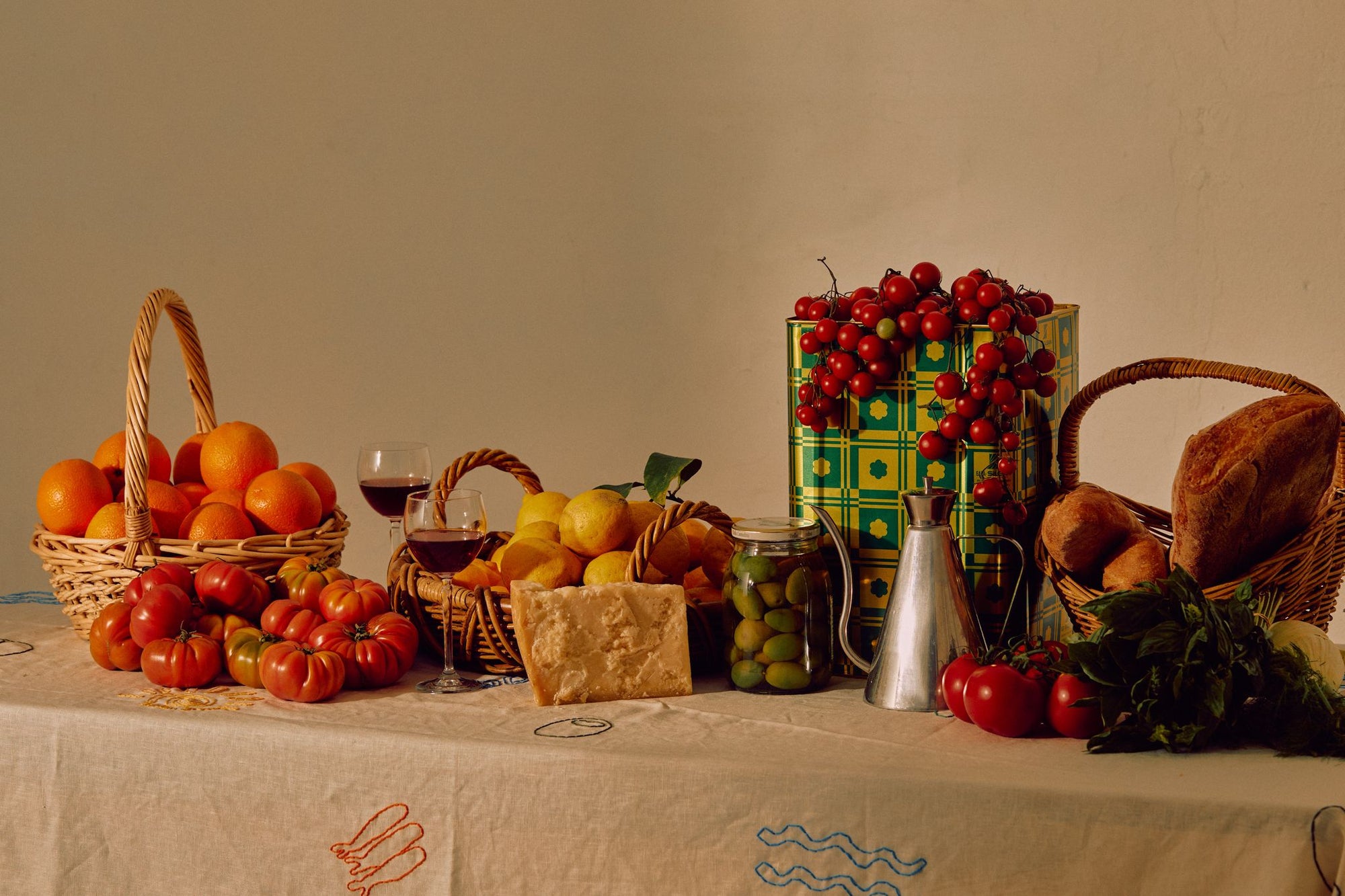 A sun-washed Mediterranean table laid with olive oil, bread, tomatoes and wine