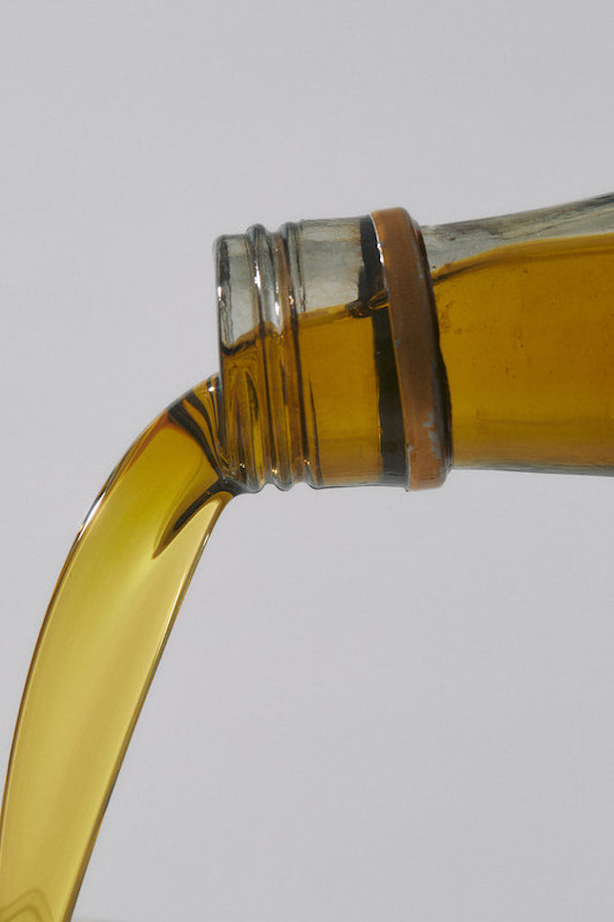 A stream of golden green olive oil pouring from the bottle