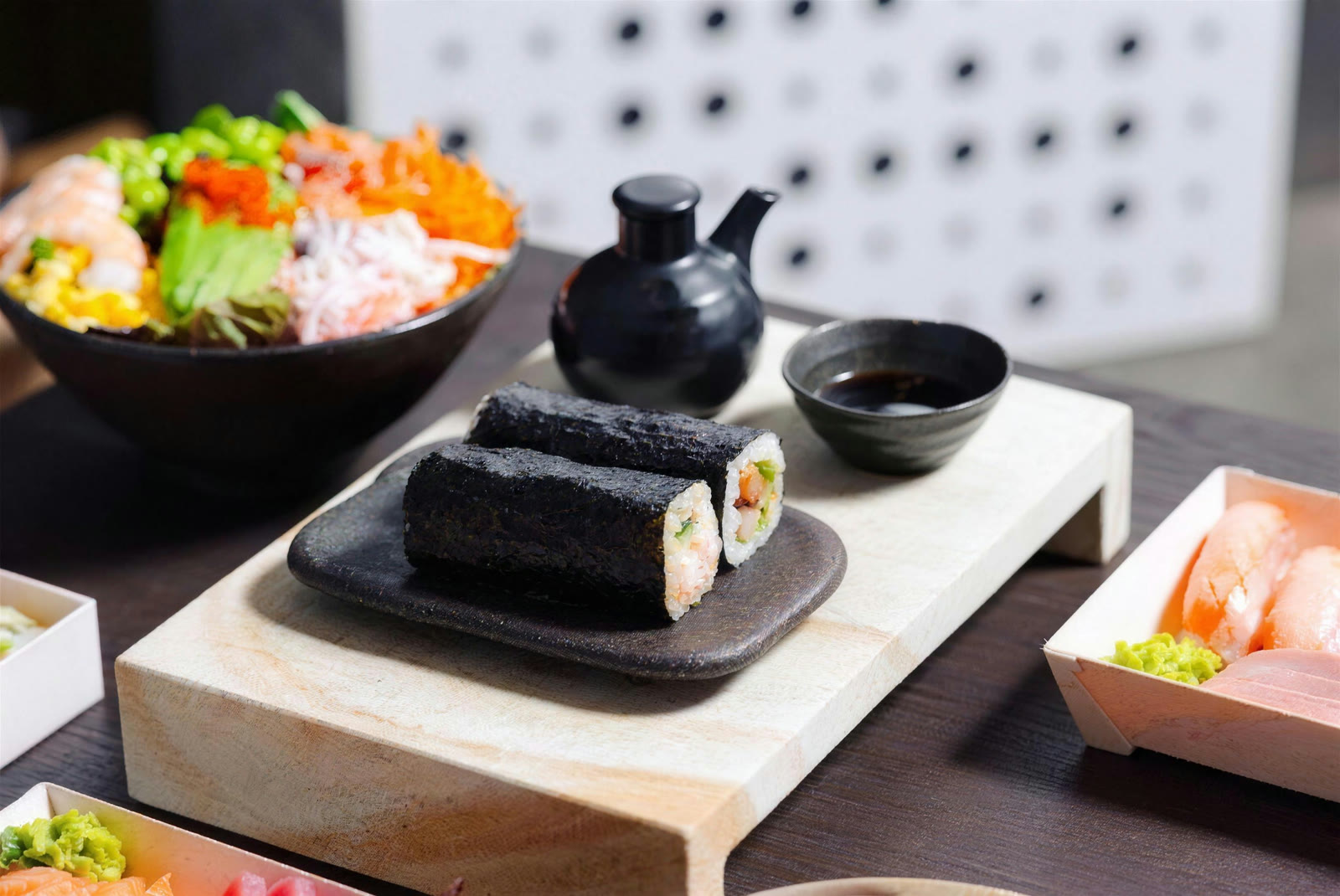 Nori rolls on a black stone plate beside a teapot