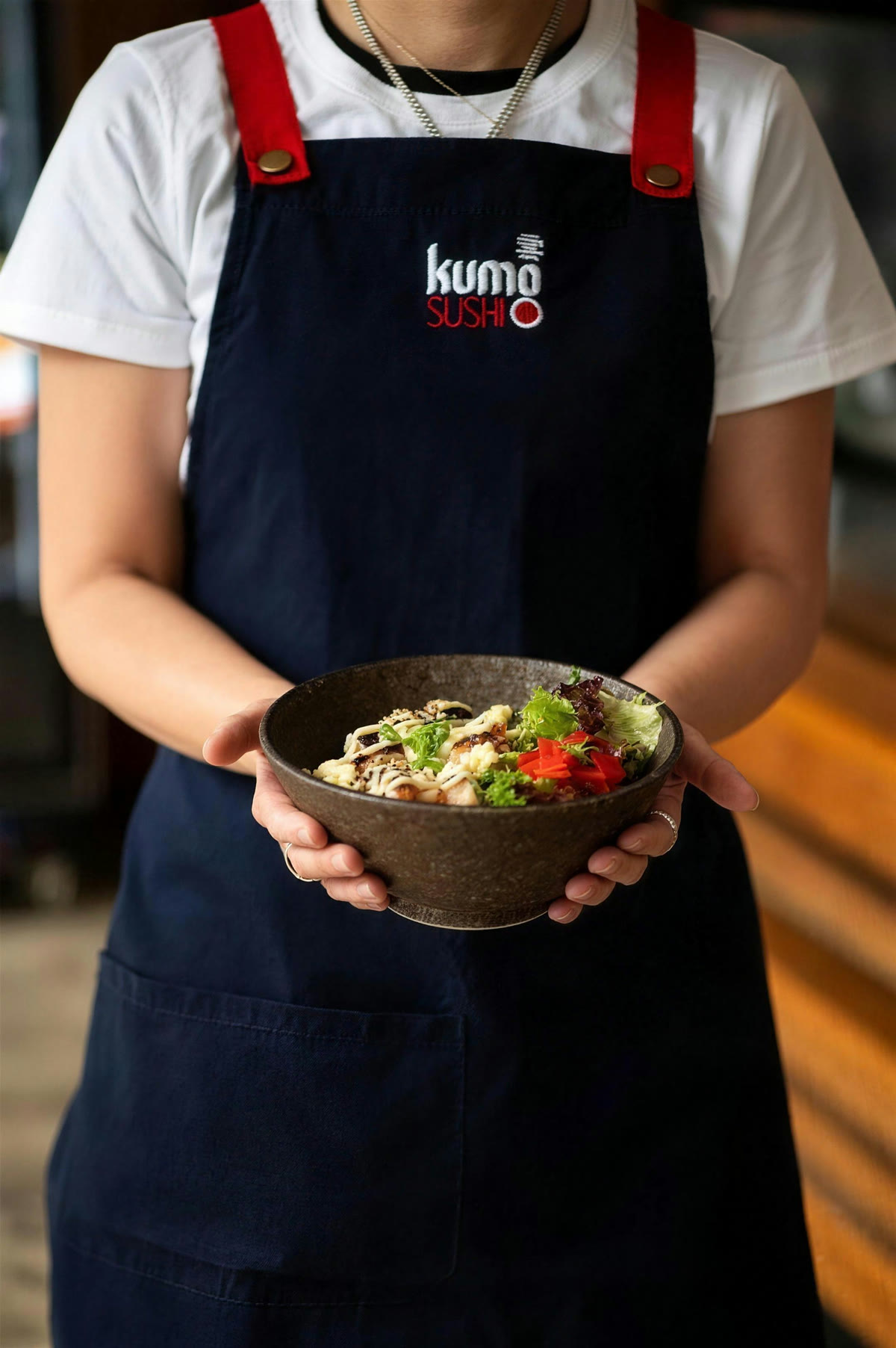 One of our team in a navy Kumo Sushi apron, holding a bowl
