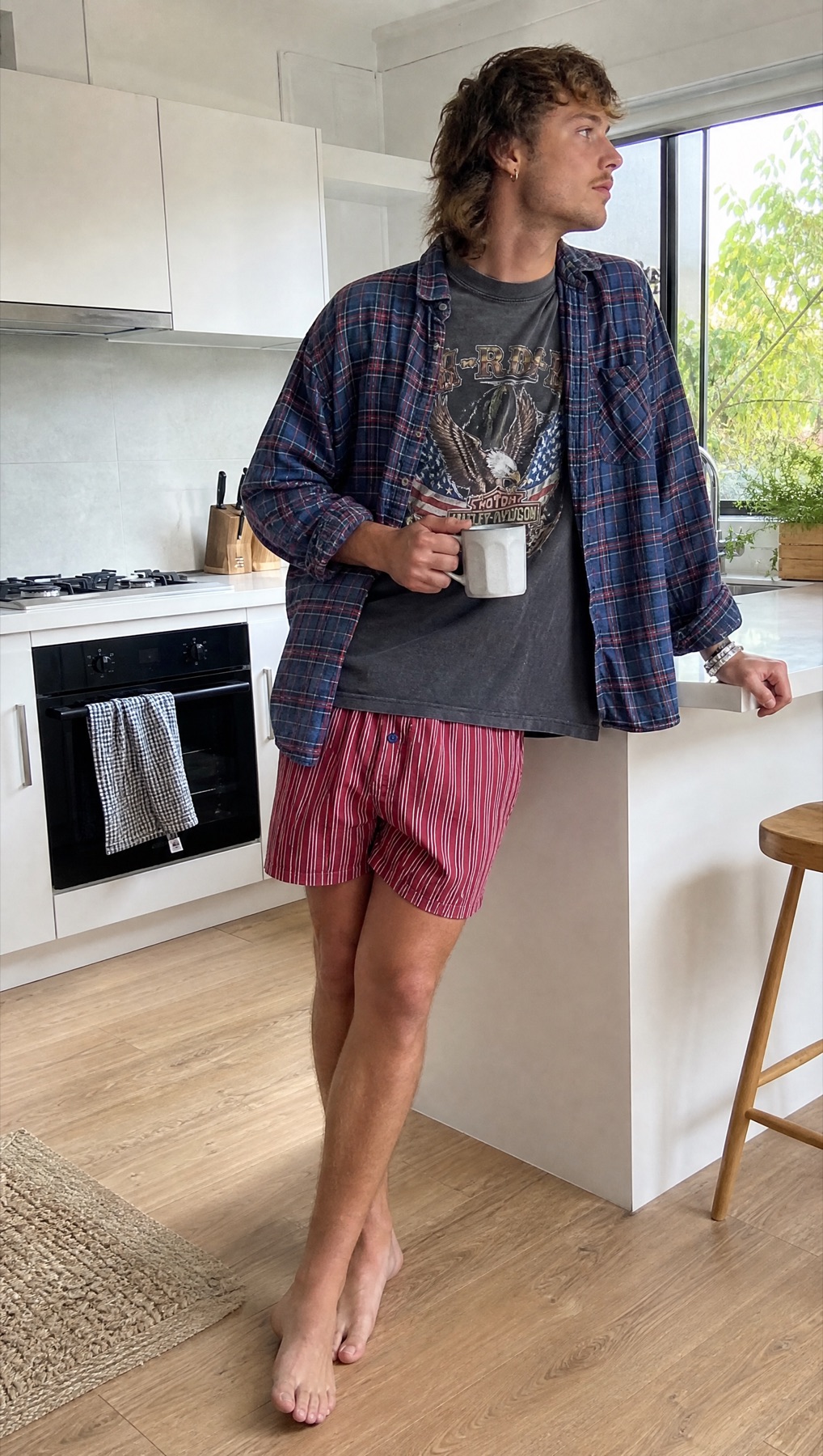 Model in a kitchen wearing red striped Mitch Dowd boxers with layered tees and an open shirt