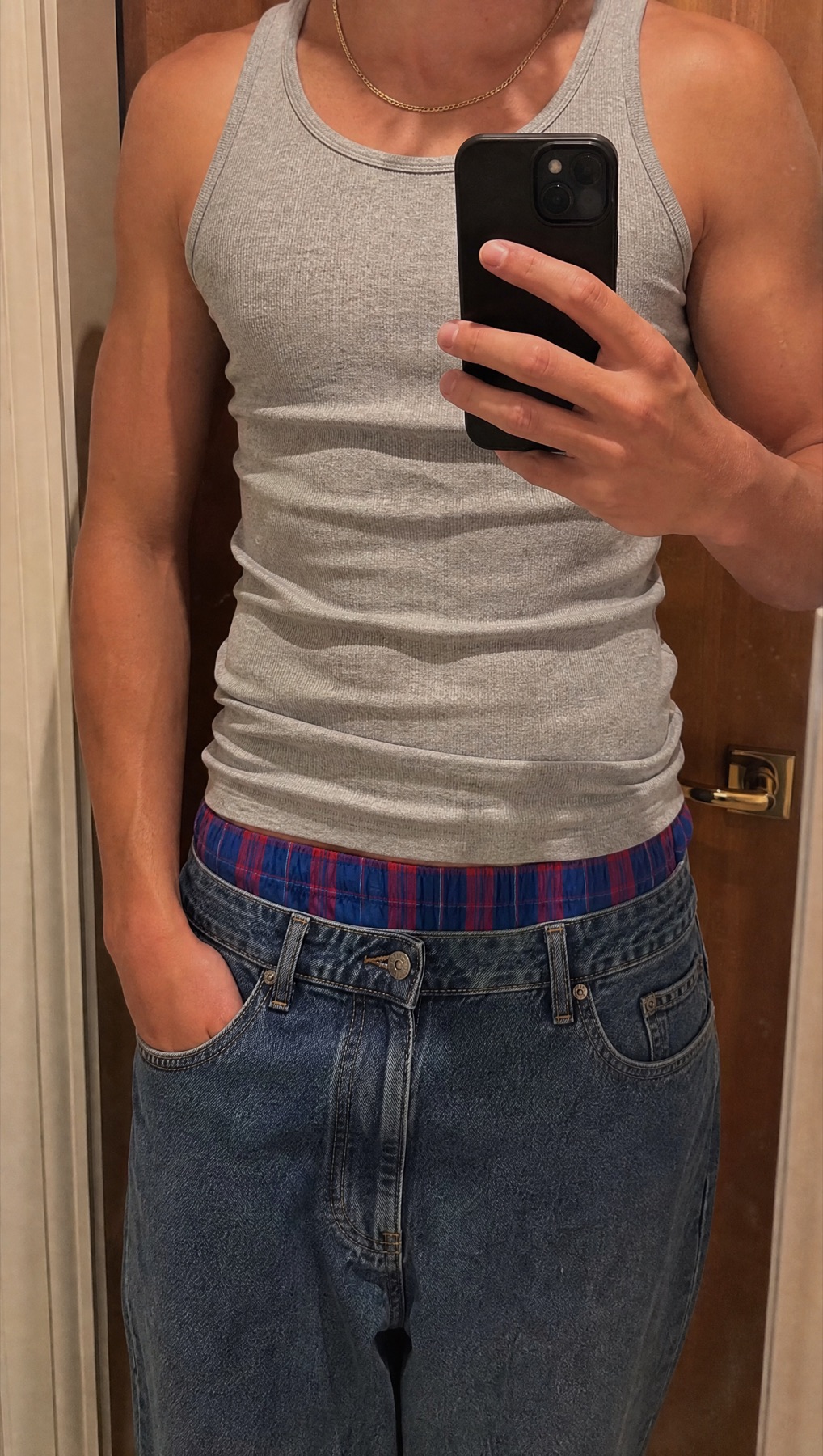Close view of a blue and red check boxer waistband worn with a grey tank and relaxed denim