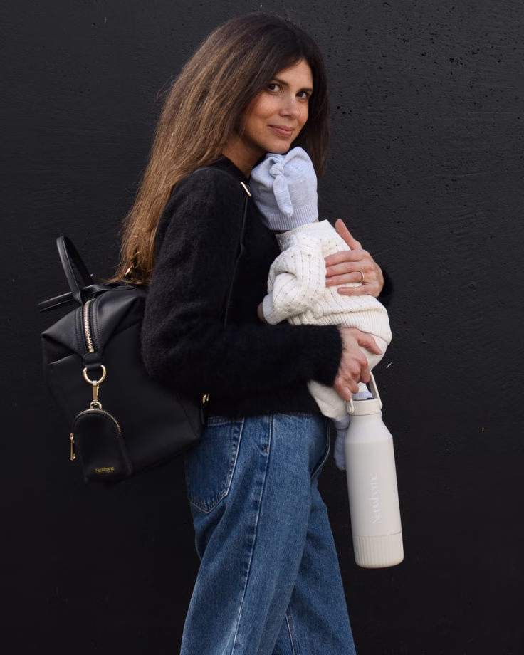 Parent carrying a baby, nappy bag and Sand Formula Feeding Thermos while out